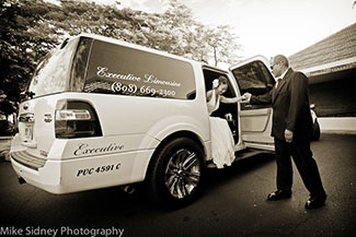 A bride being helped out of limousine by chauffeur
